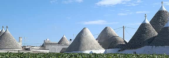 Trulli pugliesi sotto il cielo azzurro, simbolo della terra del Susumaniello