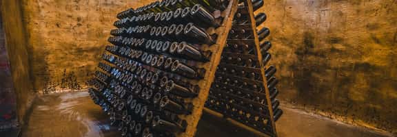 "Bottiglie di spumante in affinamento su pupitre in cantina – lavorazione tradizionale di vini premiat