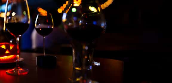 Calici di vino rosso e zucca illuminata per Halloween