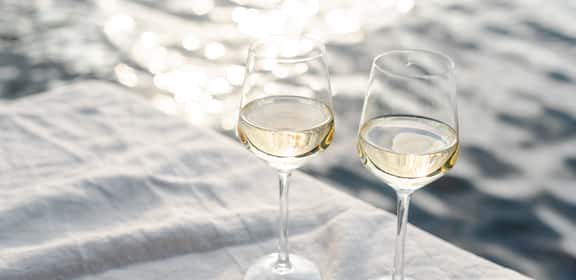 Calici di vino bianco su tavola all’aperto, atmosfera estiva