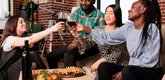 Amici brindano con calici di vino rosso, offerte vini rossi sotto i 10 euro in compagnia.