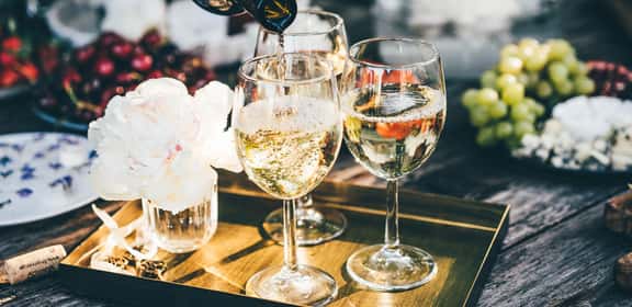 Calici di vino bianco frizzante, frutta fresca e formaggi su tavolo estivo