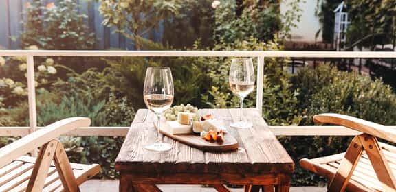 Due calici di vino bianco e formaggi su tavolo all’aperto per una cena romantica