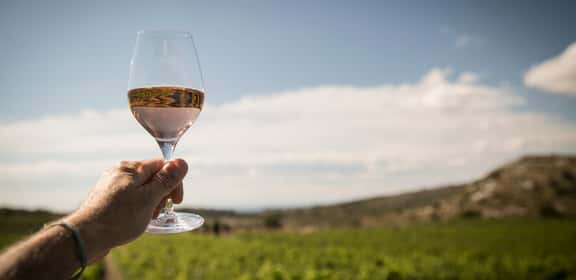 Calice di vino rosato all’aperto, cielo azzurro sullo sfondo, offerte rosati sotto i 10 euro.
