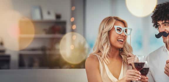 Coppia si diverte con maschere e calici di vino durante il Carnevale