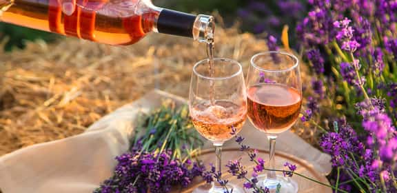 Due bicchieri di vino rosato immersi tra fiori di lavanda, simbolo di freschezza e convivialità